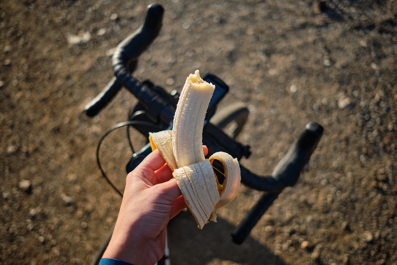 A cyclist holding a banana with a cycle background image.